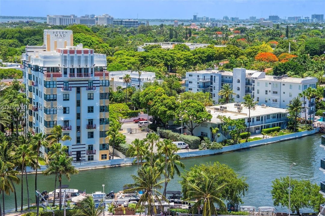 High-rise Art Deco architecture with multi-story facades, water frontage, mature palm trees, and dense urban canopy
