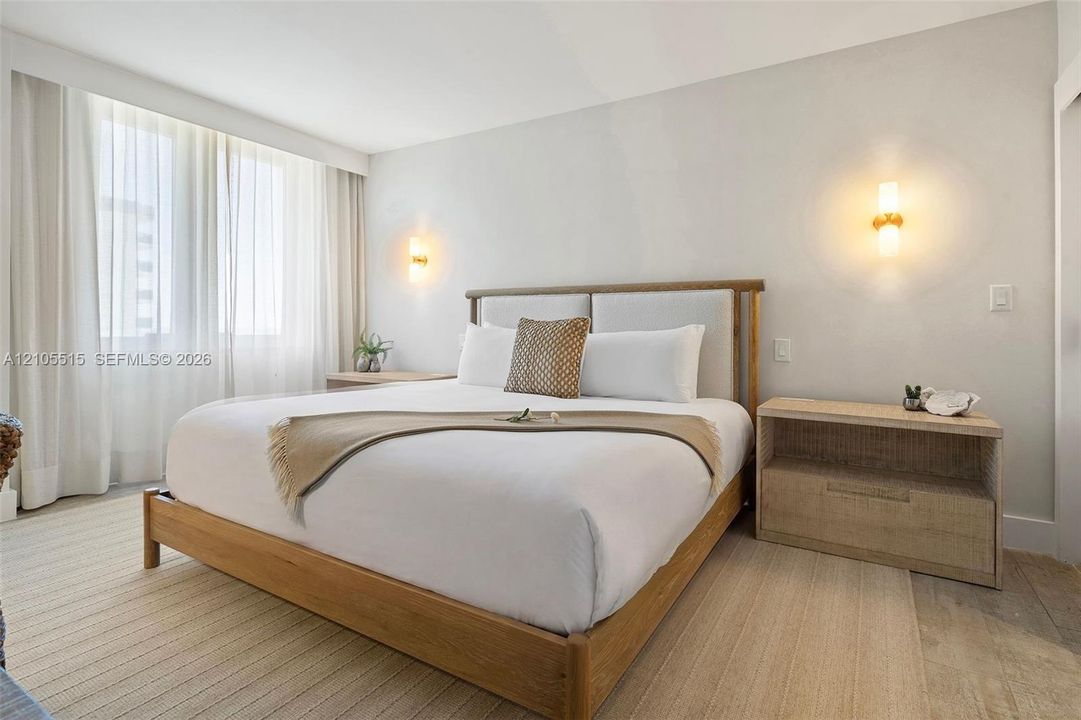 Neutral color palette, wall-to-wall carpeting, expansive windows with floor-to-ceiling drapery, and dual wall-mounted light fixtures