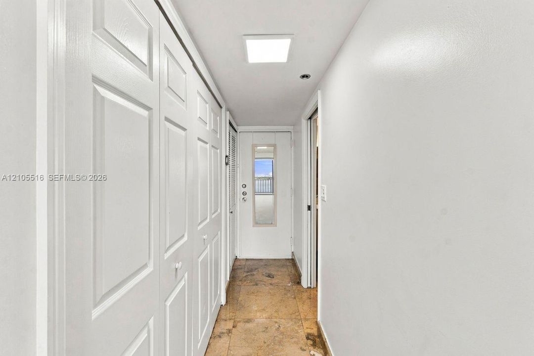 Long hallway featuring bi-fold panel doors, a built-in mirror, and recessed ceiling lighting