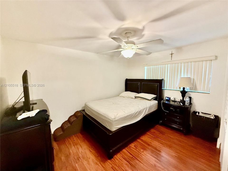 Wood-finish flooring, ceiling fan with integrated light fixture, and vertical window blinds