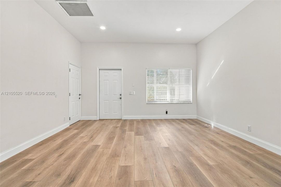 Neutral interior featuring wood-finish flooring, recessed lighting, and a multi-pane window with blinds