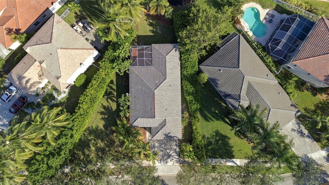 Aerial perspective featuring a tile roof, concrete driveway, and enclosed rear lanai