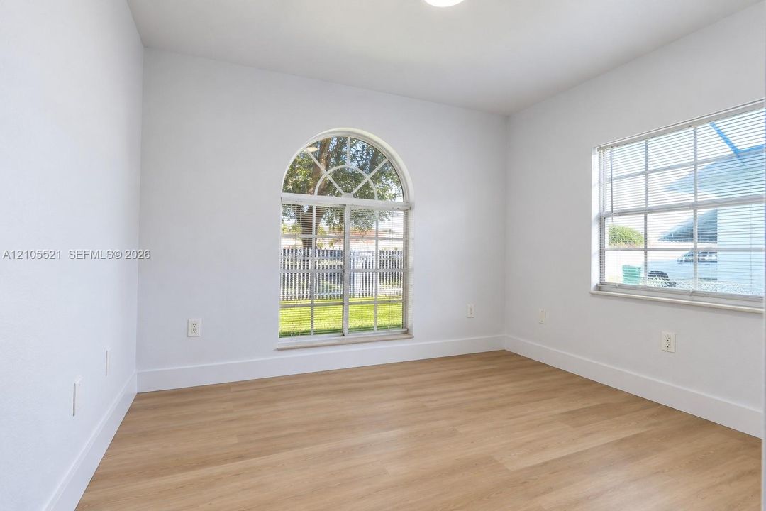 Arch-top window, wood-finish flooring, white baseboards, recessed lighting, white walls
