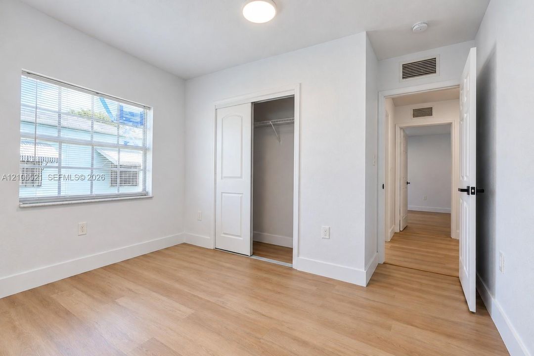 Recessed lighting, wood-finish flooring, white walls, and a sliding door closet
