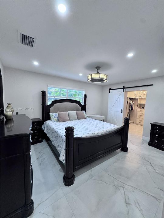 Recessed lighting with a ceiling fan, window with glass blocks, white wood-finish barn door, and large format tile flooring