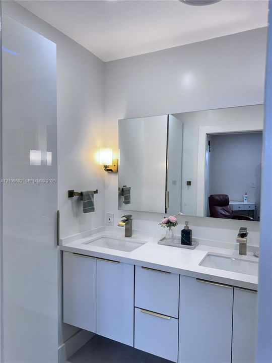 Double vanity with white cabinetry, integrated sinks, and polished chrome faucets