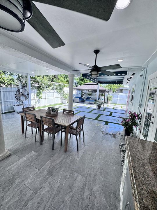 Covered patio with integrated ceiling fans, recessed lighting, and a built-in outdoor kitchen featuring a granite countertop