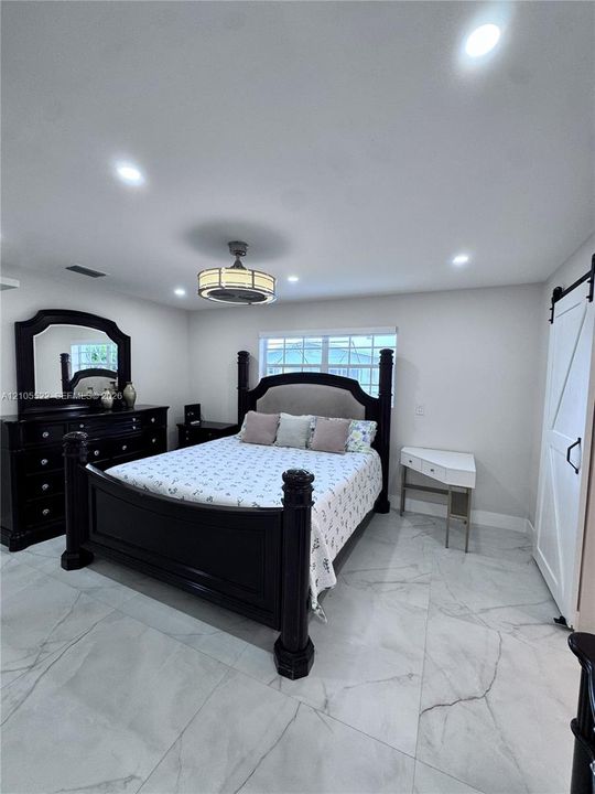 Recessed lighting, ceiling fan with integrated light, marble-look tile flooring, and a white barn door