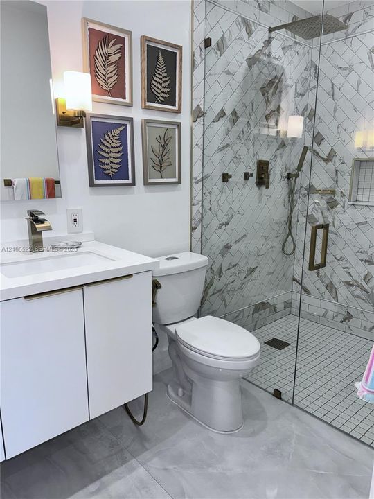 Walk-in shower with glass enclosure, herringbone tile, and rain shower head