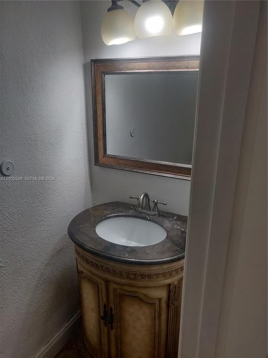 Curved vanity with an integrated sink, framed mirror, and a three-light fixture