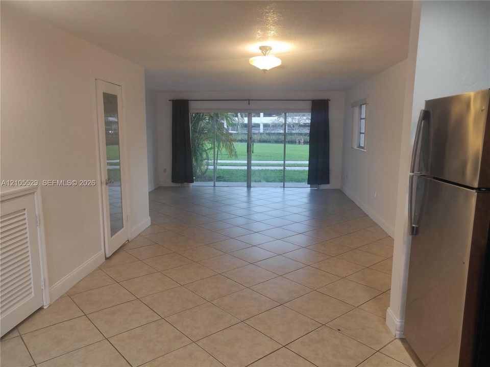 Tile flooring, sliding glass door, stainless steel refrigerator, recessed window, and ceiling-mounted light fixture