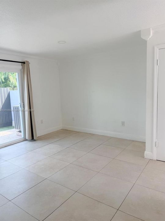 Recessed lighting, crown molding, white walls, light-toned tile flooring, and a sliding glass door