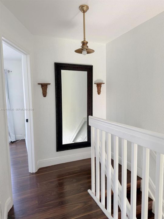 Wood-finish flooring throughout the hallway and staircase, complemented by white painted railings