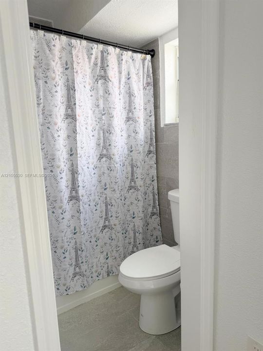Tiled shower surround with a white toilet and light-toned flooring