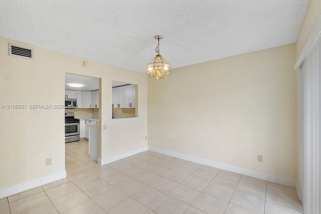 Recessed kitchen with white cabinetry, stainless steel appliances, and a pass-through window