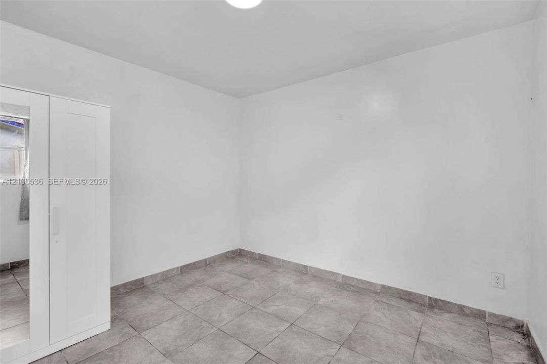 Interior room featuring large-format neutral tile flooring and crisp white wall finishes