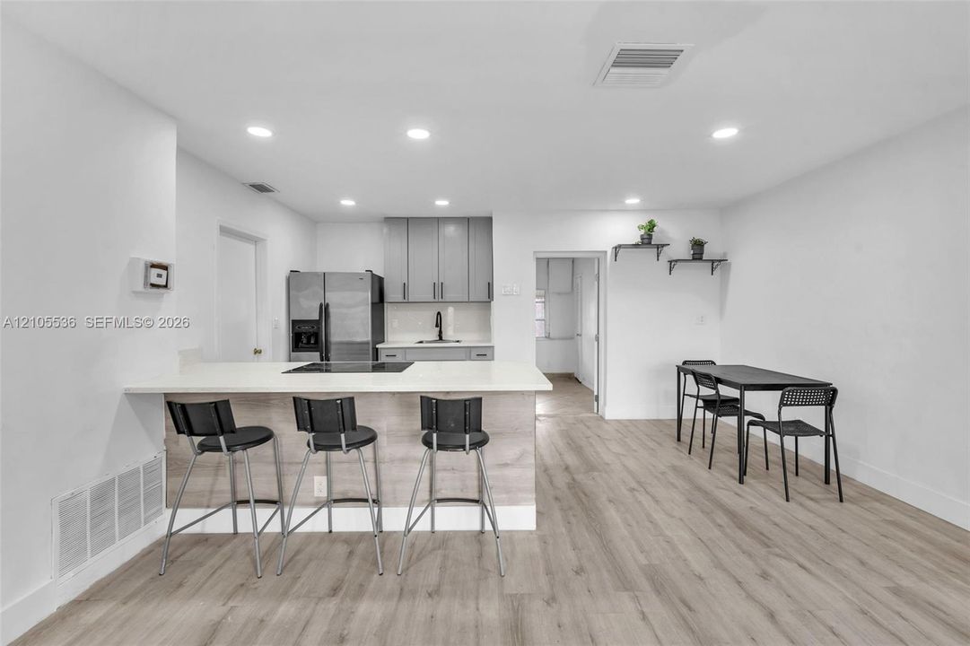 Kitchen featuring a wood-finish island with a stone countertop, grey cabinetry, stainless steel refrigerator, recessed lighting, and wood-finish flooring