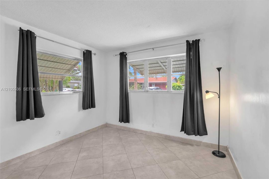 Neutral-toned room featuring large windows, diamond-patterned tile flooring, and a textured ceiling finish