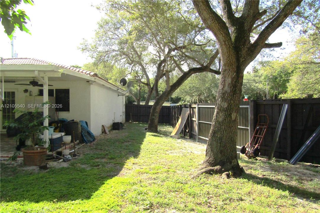 Expansive lawn area featuring mature trees and a privacy fence