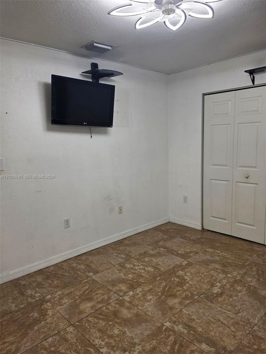Tile flooring with a neutral finish, white walls, and a ceiling-mounted fan with integrated lighting