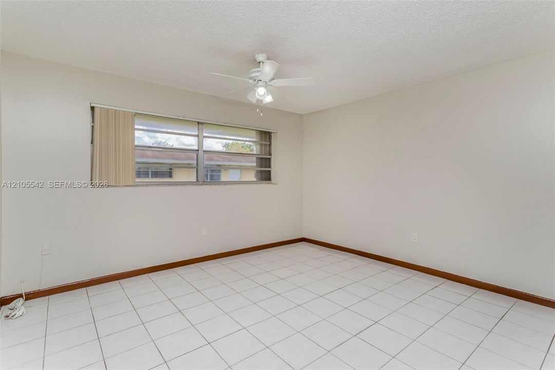 White tile flooring, a window with horizontal blinds, and a ceiling fan with light fixture