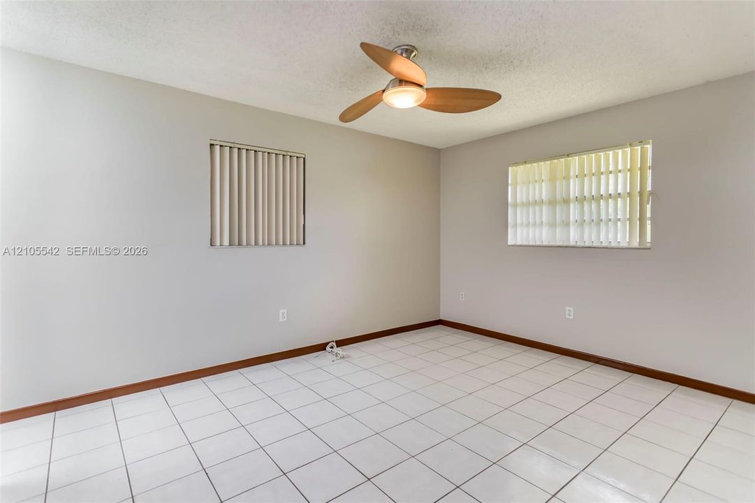 White square tile flooring, light gray wall paint, and two windows with vertical blinds