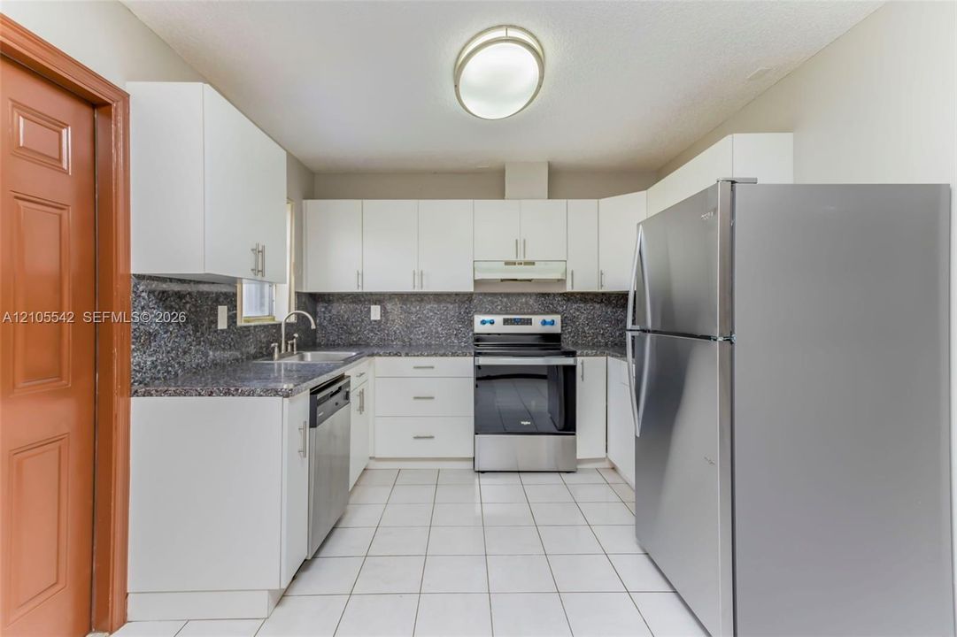 U-shaped kitchen with white cabinetry and dark stone countertops