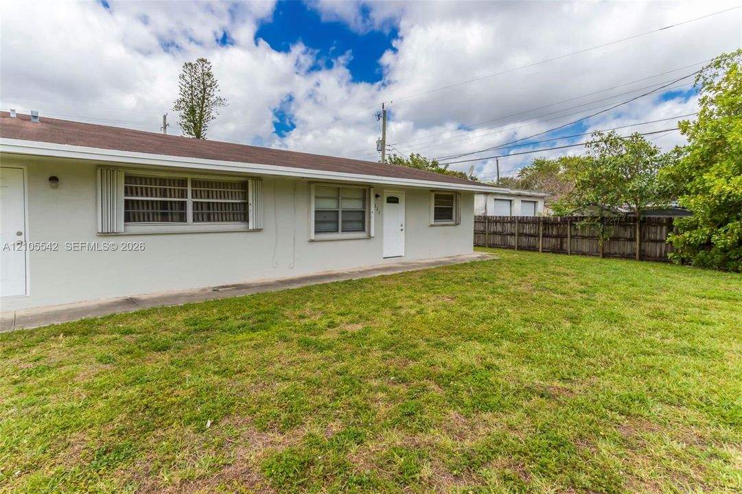 Expansive yard with mature landscaping and a wood fence