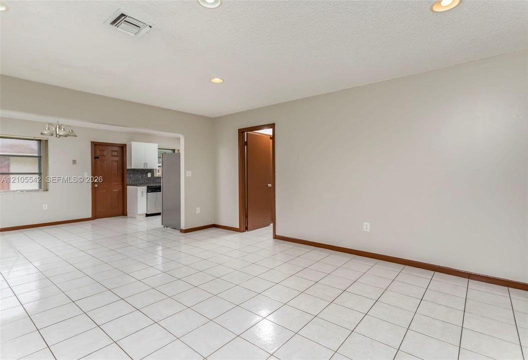White tile flooring throughout, recessed lighting, and a kitchen with stainless steel appliances