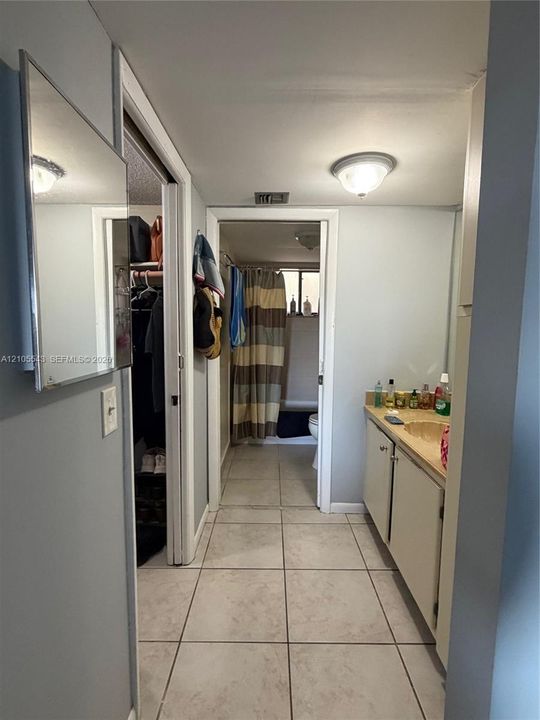 Ceramic tile flooring, vanity cabinet with integrated countertop, wall-mounted mirror, and flush-mount ceiling lighting