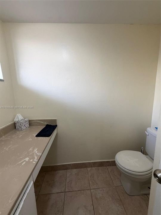Built-in vanity featuring a stone-composite countertop and ceramic tile flooring