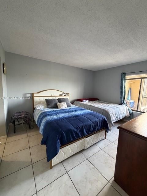 Room featuring large-format ceramic tile flooring, neutral grey wall paint, and a sliding glass door providing natural light