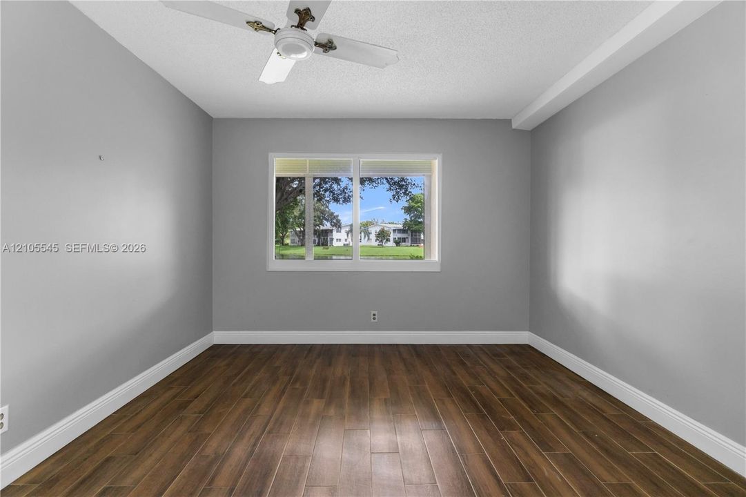 Wood-finish ceramic flooring, white trim, a ceiling fan, and a prominent window