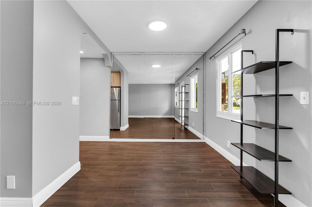 Recessed lighting, full-height wall mirror, wood-finish flooring, built-in shelving, and white trim