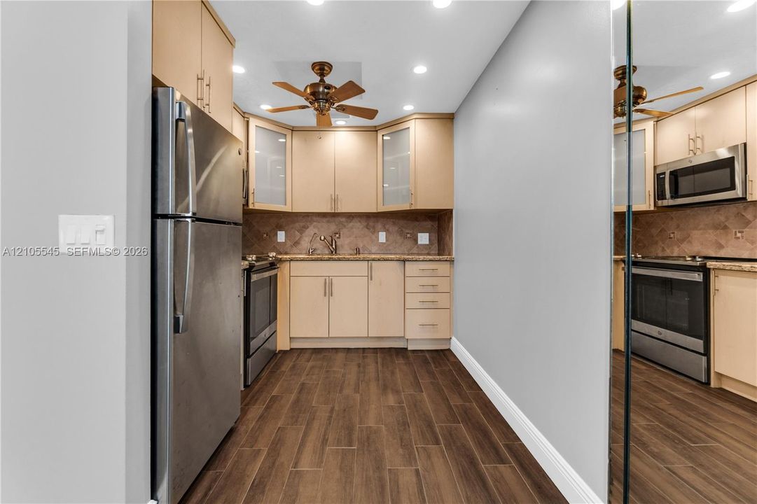 Kitchen featuring stainless steel appliances, wood-finish flooring, recessed lighting, a ceiling fan, and ample cabinetry