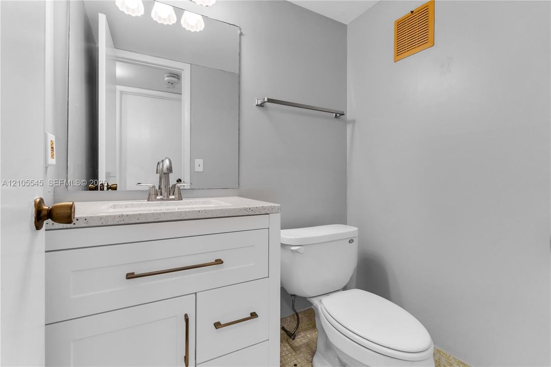 White vanity with bronze hardware, a white countertop, and a chrome faucet