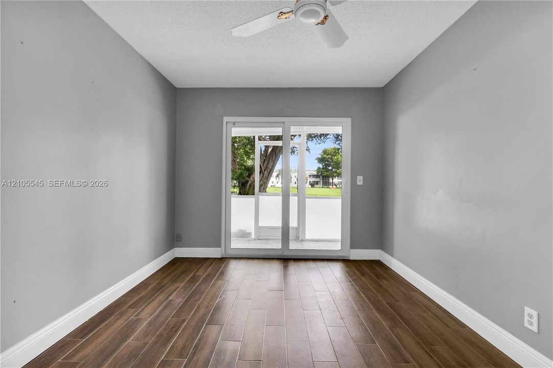 Wood-finish ceramic flooring, neutral gray walls, bright white trim, and a ceiling fan
