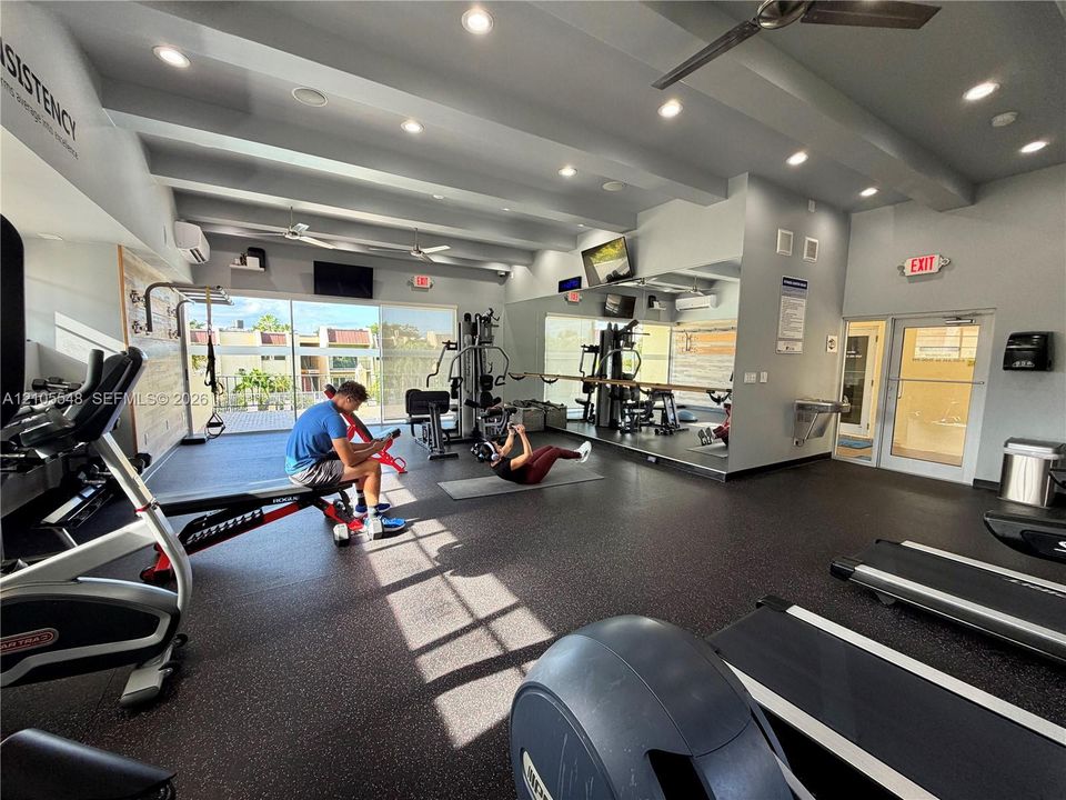 Gym featuring rubber flooring, recessed ceiling lighting, full-wall mirrors, and floor-to-ceiling glass windows