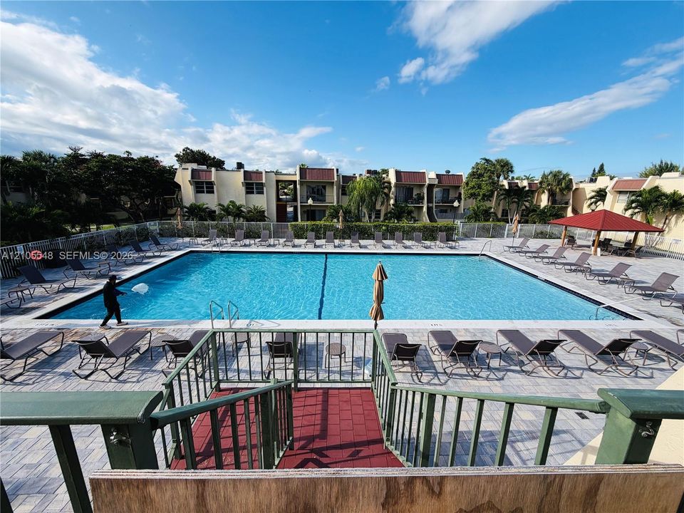 Community swimming pool with a paved deck, perimeter fencing, and a covered pavilion