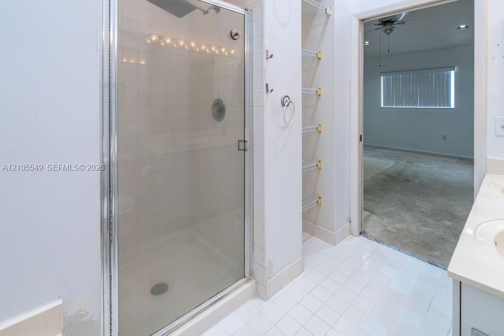 Walk-in shower with clear glass enclosure and overhead lighting