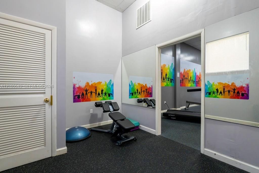Recessed lighting, louvered door, rubberized flooring, mirrored wall, and an open doorway