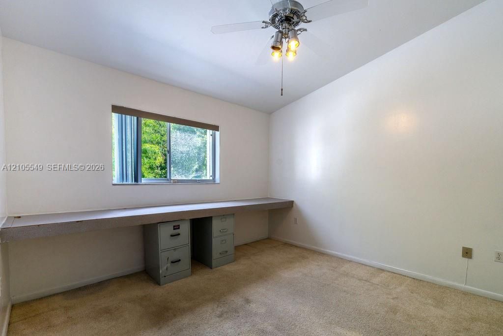 Recessed window with horizontal blinds, built-in desk counter, and ceiling fan with integrated lighting