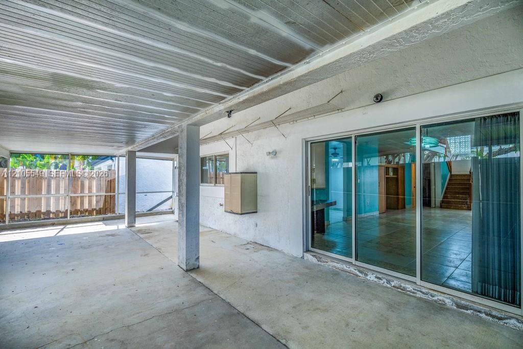 Covered concrete patio with a slatted ceiling, a concrete floor, and multiple support columns