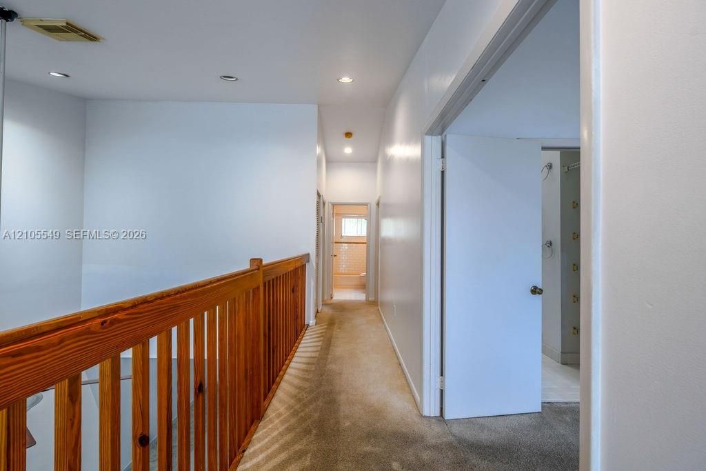 Hallway with recessed lighting, wood railing, and carpet flooring