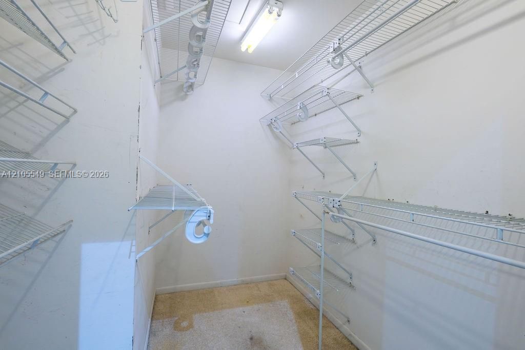 Walk-in closet with wire shelving system, multiple hanging rods, and integrated overhead lighting