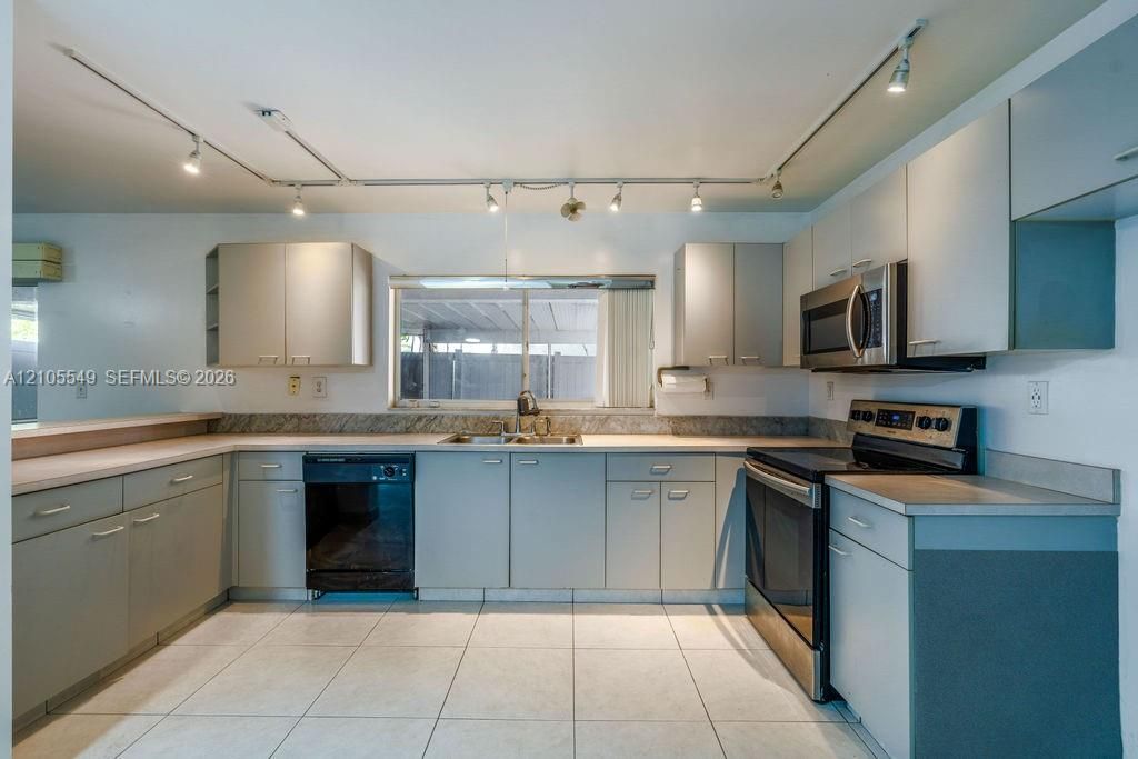 Kitchen featuring track lighting, light-toned cabinetry, a stainless steel microwave, a stainless steel range, and tile flooring