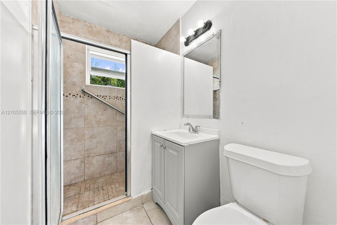 Tiled shower enclosure with glass sliding door and grab bar