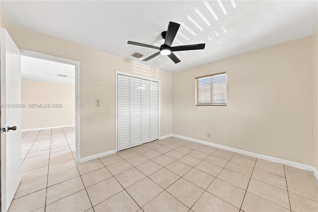 Tile flooring throughout, a ceiling fan with integrated lighting, and a window with blinds