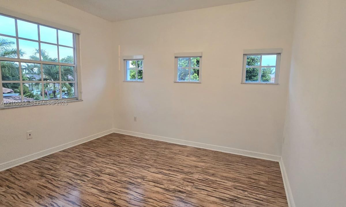 Room featuring wood-finish flooring, a large multi-pane window, and three additional multi-pane windows