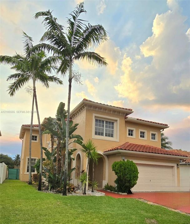 Two-story stucco exterior featuring a clay tile roof, arched entryway, and multi-paned windows